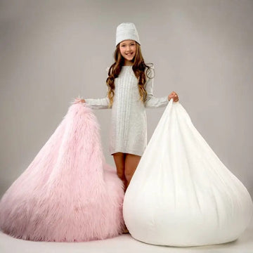 Child holding a pink and a white bean bag chair against a plain background