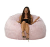 Woman sitting on a fluffy pink bean bag chair against a white background