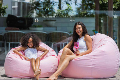 girls sitting on pink beanbag chairs by the pool
