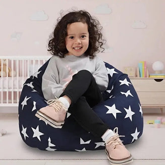 Child sitting on a navy blue bean bag with white star pattern in a room with a crib and shelves.