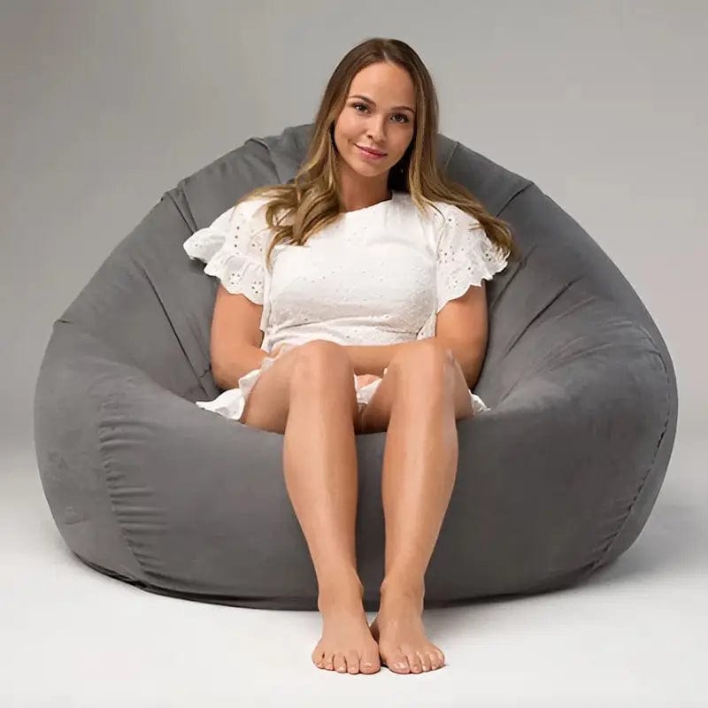 Woman sitting inside a large gray bean bag chair on a plain background