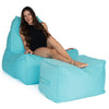 Woman sitting on a capri blue Copacabana bean bag chair with ottoman on a white background