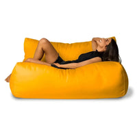 Woman lying on a large yellow bean bag chair against a white background