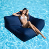 Woman relaxing on a navy beanbag pool float in clear blue water