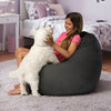 Woman sitting on a bean bag with a small white dog in a bedroom setting