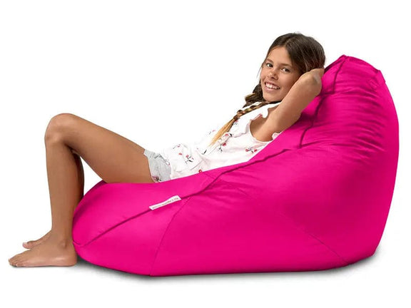 Young girl sitting in a bright pink bean bag chair on a white background