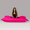 Woman sitting on a large pink bean bag against a gray background