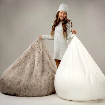Child holding a fluffy gray bean bag and a white bean bag against a neutral background