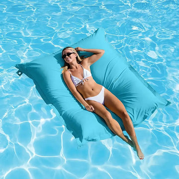 Woman lounging on a blue pool float in clear blue water
