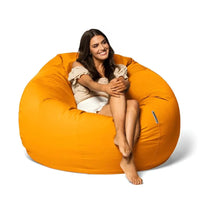 Woman sitting on a large orange bean bag chair against a white background