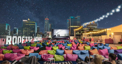 Outdoor movie screening with colorful chairs and city skyline in the background